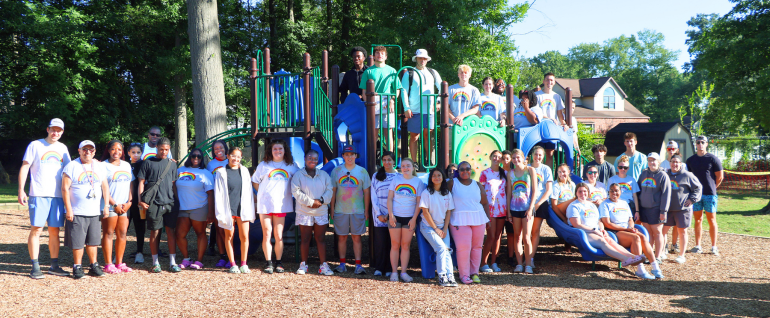 A large group of Camp Hope staffers on the Camp Hope playground on a sunny morning in 2024.