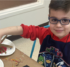 A boy sitting at a table working on a painting project.