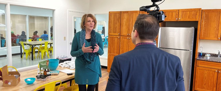 A woman standing in front of a TV camera at Studio Arc.