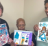 Three women holding paintings on canvases