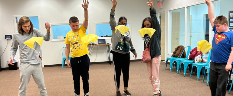 Teenagers tossing yellow parachutes