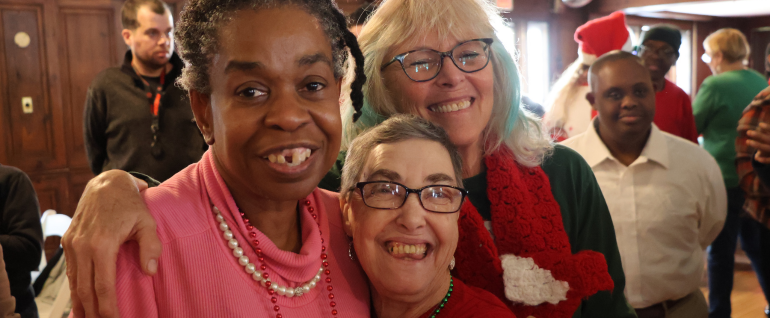 Three women in holiday attire smile together