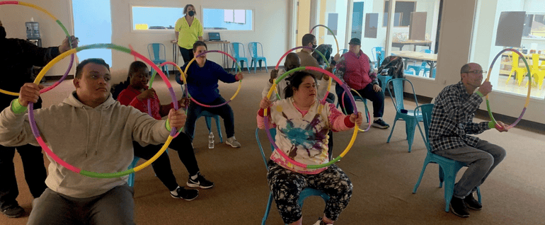A group of people sitting in chairs and holding hula hoops in front of them.