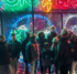 A group standing outdoors at night time in front of a "Magic of Lights 2024" light-up display.