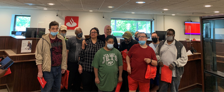 A group of people gathered and smiling for a photo in the lobby of a Santander Bank.