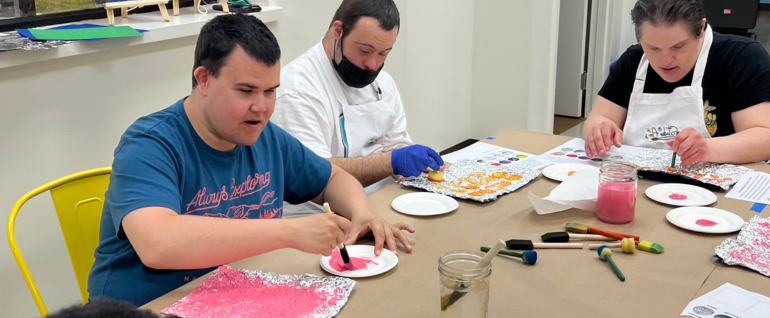 Day program participants creating works of art using paint and aluminum at Studio Arc.
