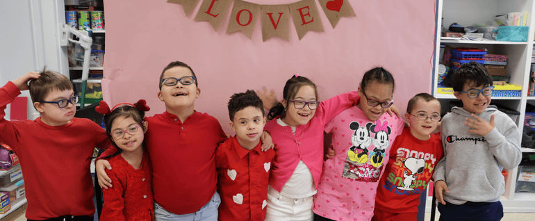 Stepping Stones students together wearing red and pink, under a 
