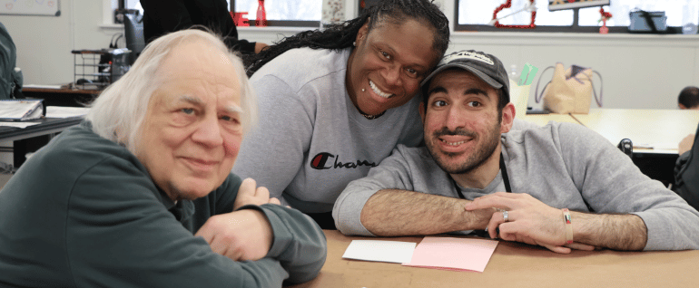 Two men smile with an Arc staff member at SYA Day Program