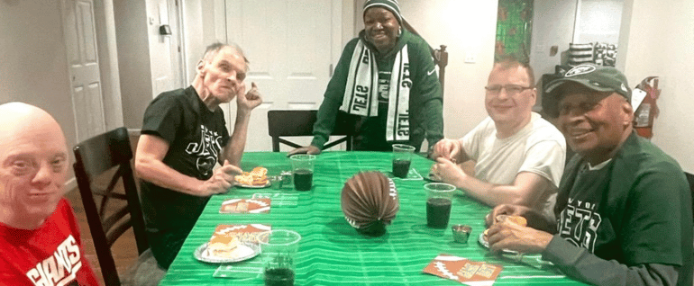 Four men and a staff member gathered around a football-decorated table for the Super Bowl