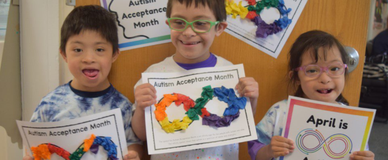 Three children holding papers that have colorful collages on them and say 