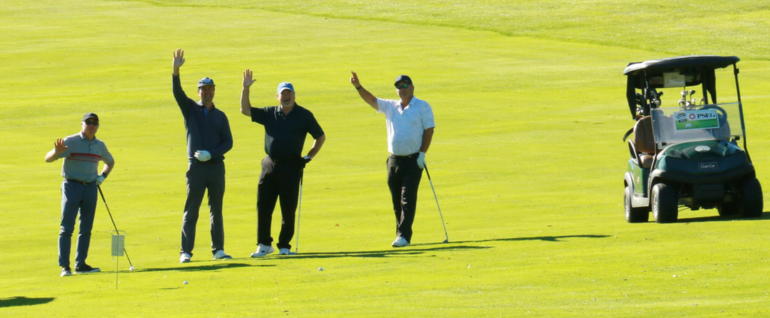 Four golfers waving with all green grass in the background. A golf cart is parked, with a PSEG logo on the front.