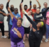 A group of people gathered together raising their hands in the air.