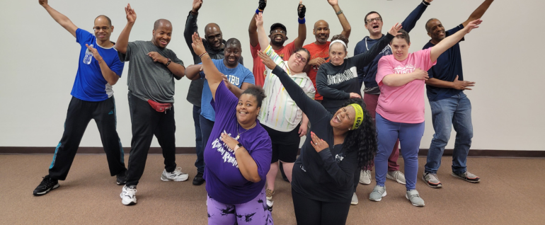 A group of people gathered together raising their hands in the air.