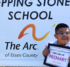 A boy standing in front of a sign for Stepping Stones School holding up a sign that says "First Day of Primary."