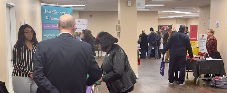 Tables in a large room with information displays and people in discussion at the tables.