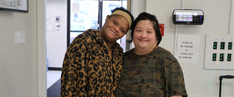 Two women smiling by a Day Program entrance.