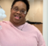 A woman in a pink sweater holds up a craft of a cotton-ball cloud with snowflakes underneath.