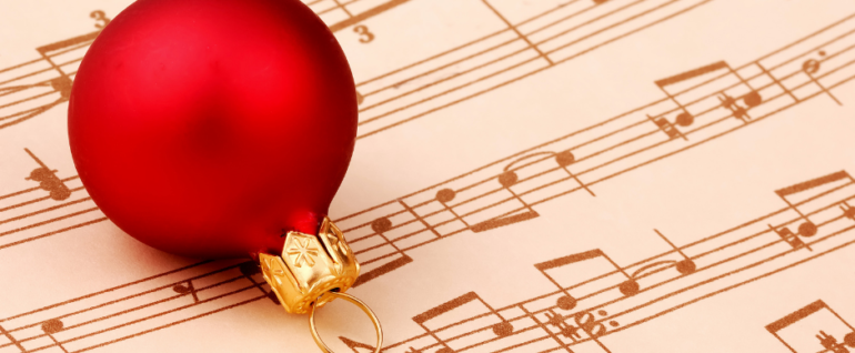 A red bulb ornament on top of a piece of sheet music.