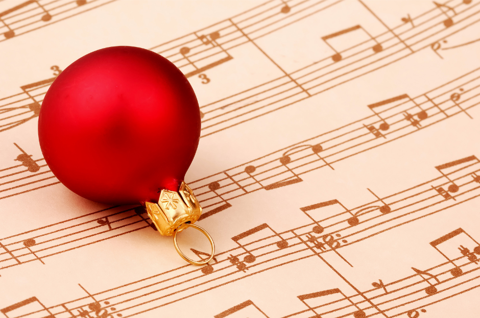 A red bulb ornament on top of a piece of sheet music.