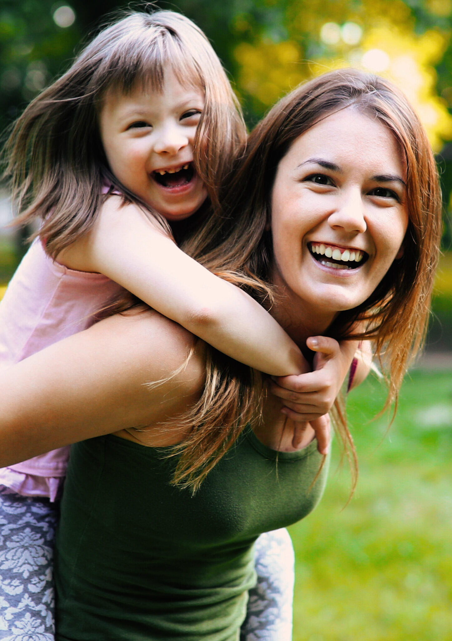 A child riding on a woman's back, both with big smiles.