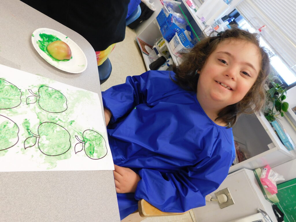 Stepping Stones student doing an apple stamping art project