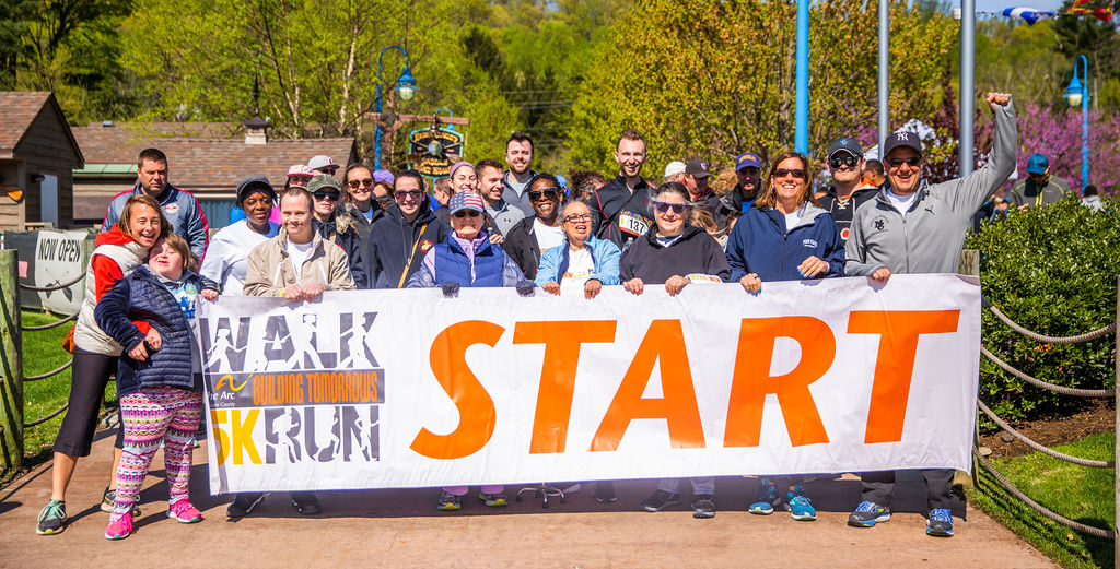 A group of people on a sunny day standing behind a giant banner that says "START."